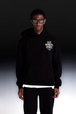 Person wearing a black hoodie with text, standing