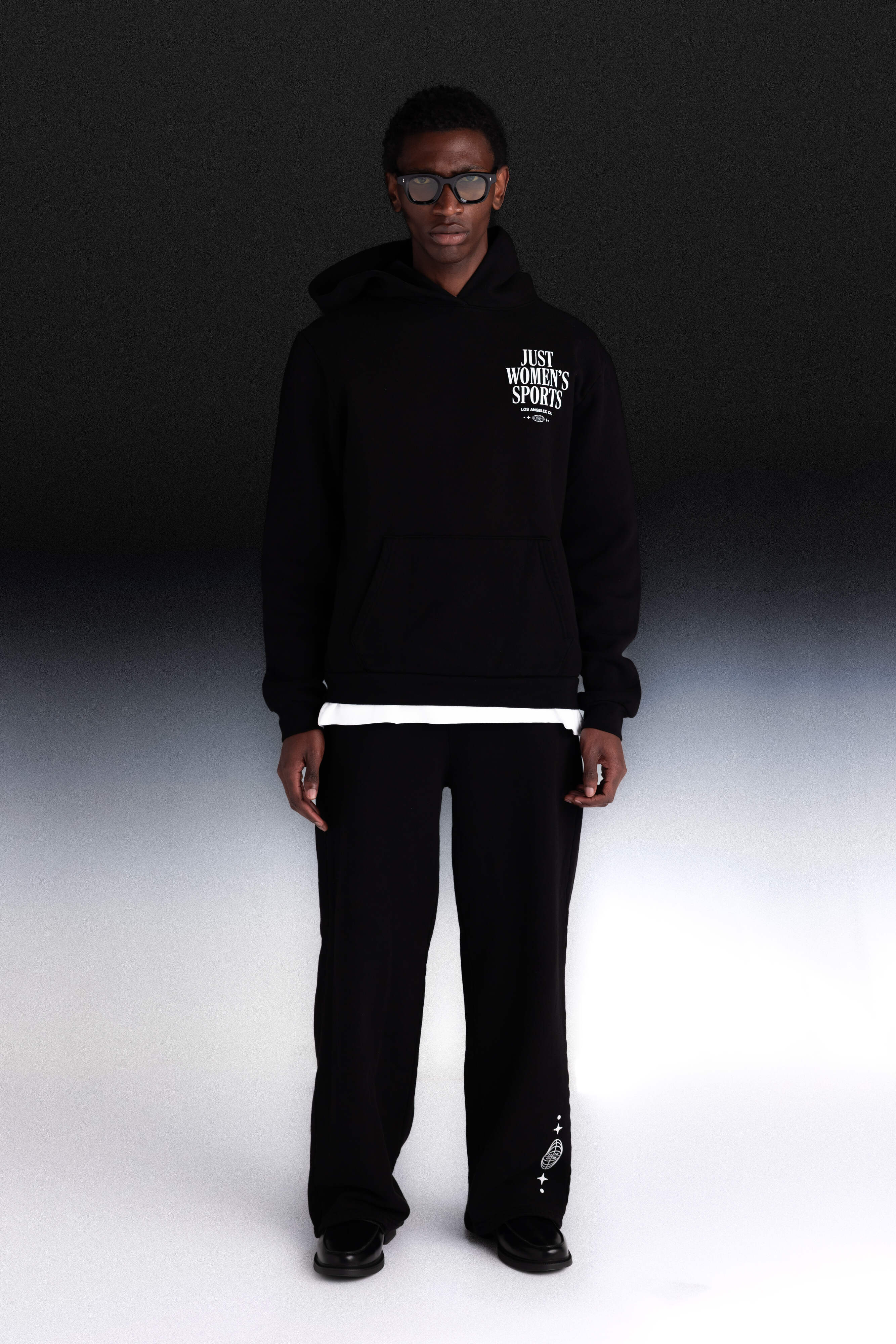 Person wearing a black hoodie with text and black pants