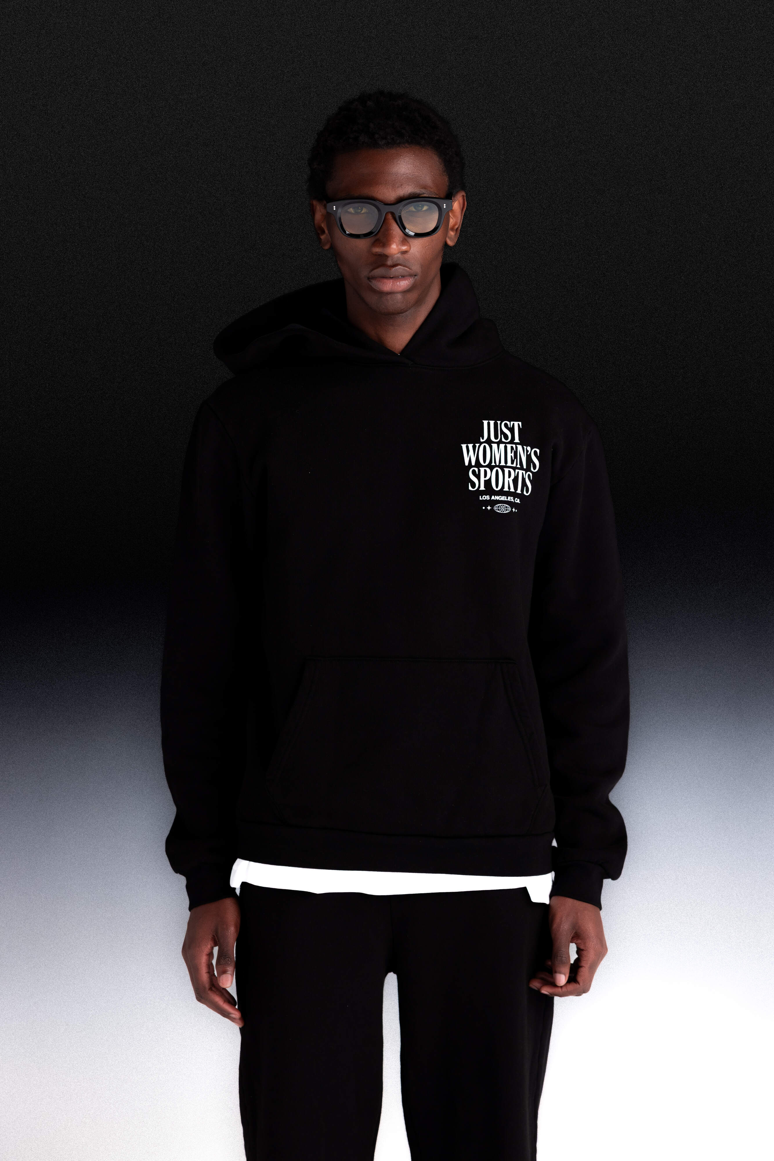 Person wearing a black hoodie with text, standing