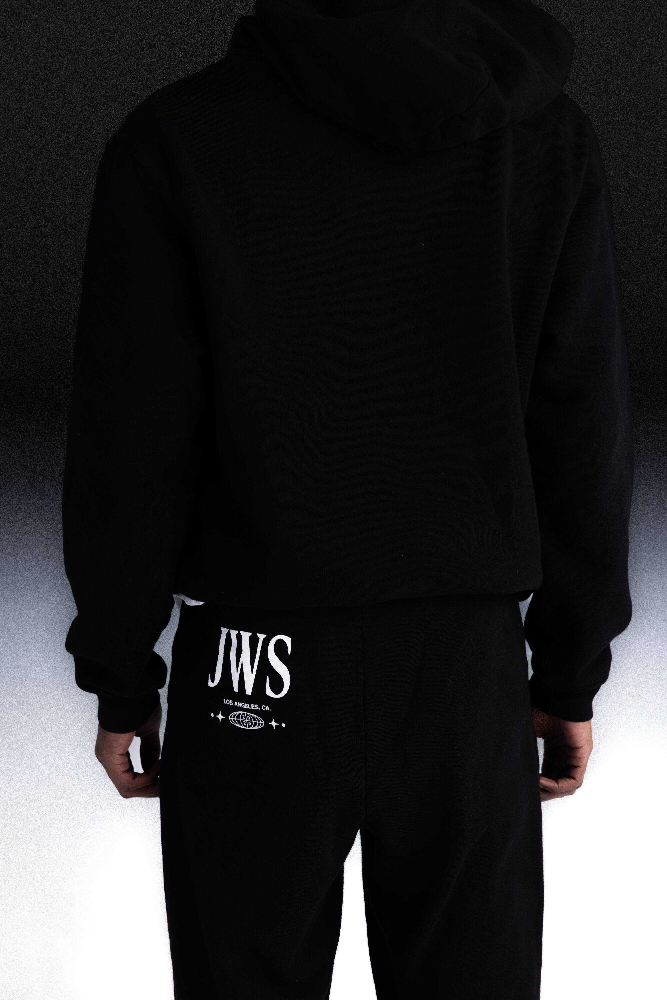 Person wearing black joggers with JW logo