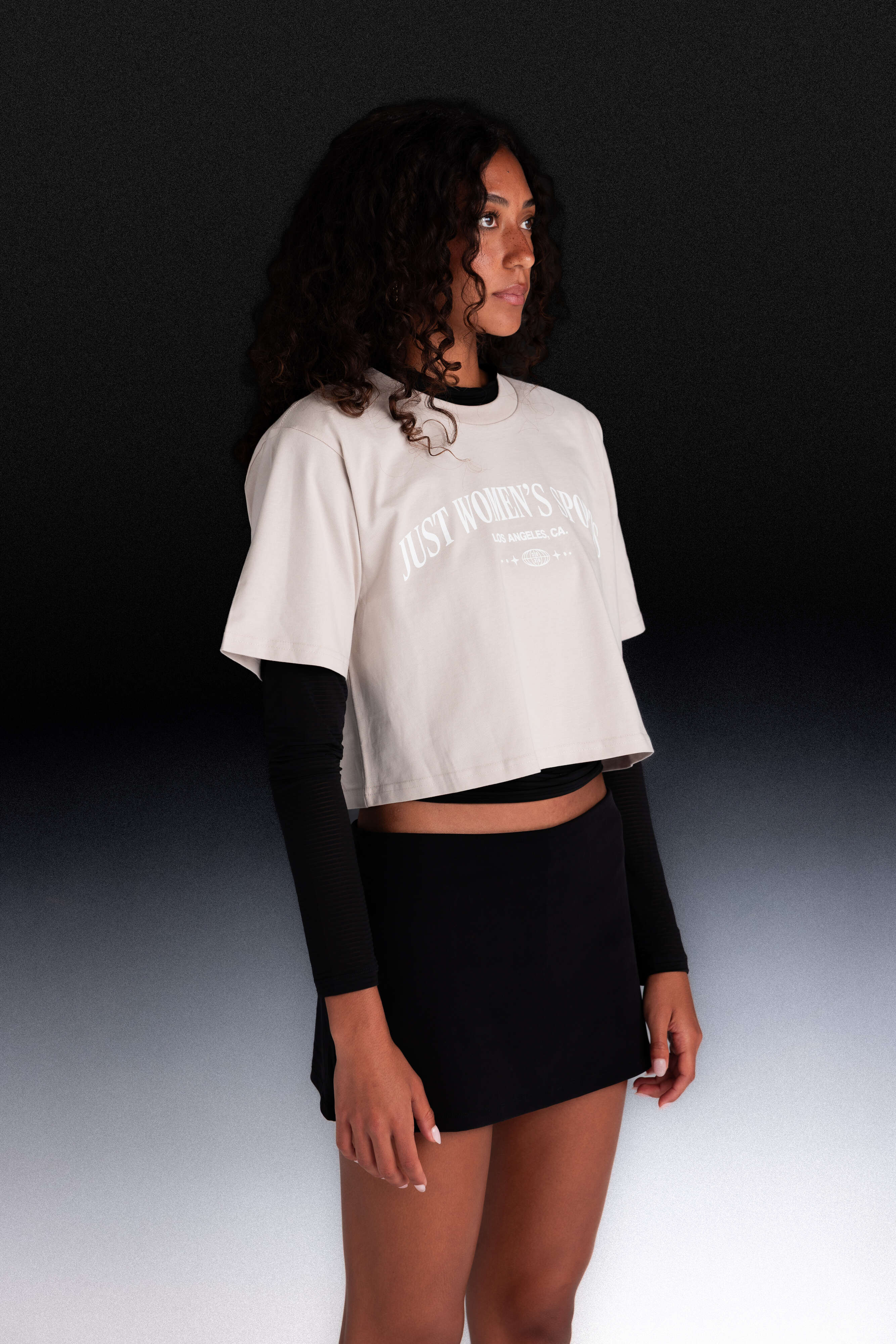 Woman wearing a white cropped t-shirt with text and black long-sleeve underneath