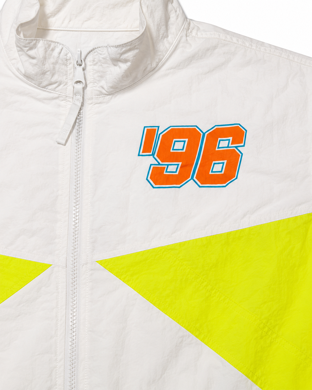 Close-up of a white zip-front jacket with a large orange '96 graphic outlined in blue on the chest and bright neon yellow geometric panels across the lower front.